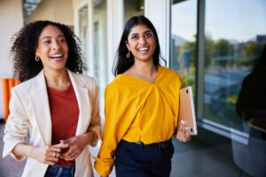 two colleagues walk together through hall way.